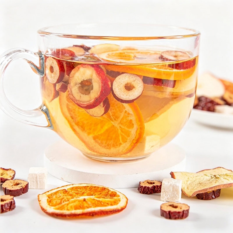 Brewed Apple & Poria Cocos tea in a clear glass cup with visible fruit and herb slices
